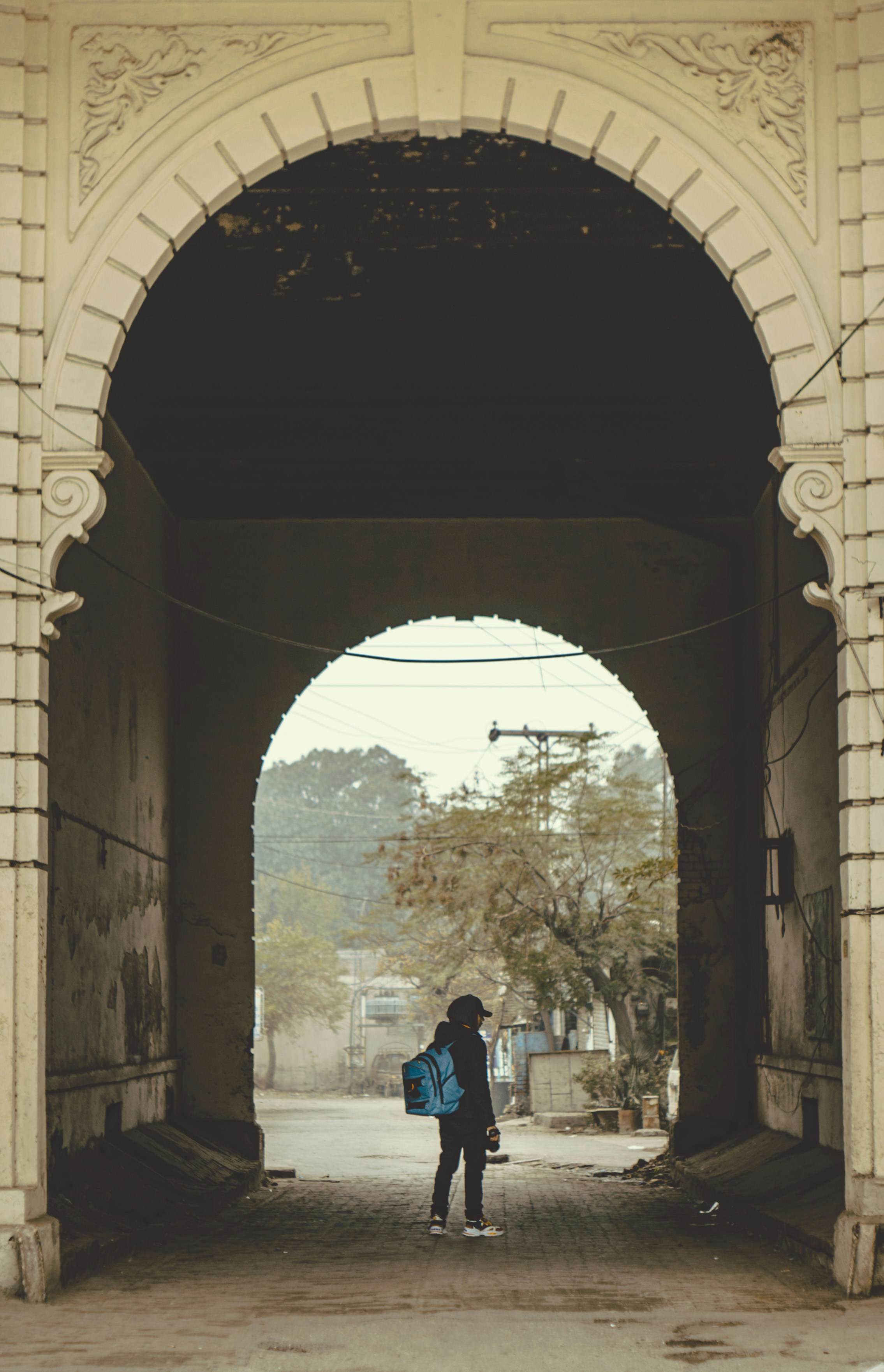 a person with a backpack standing under an arch