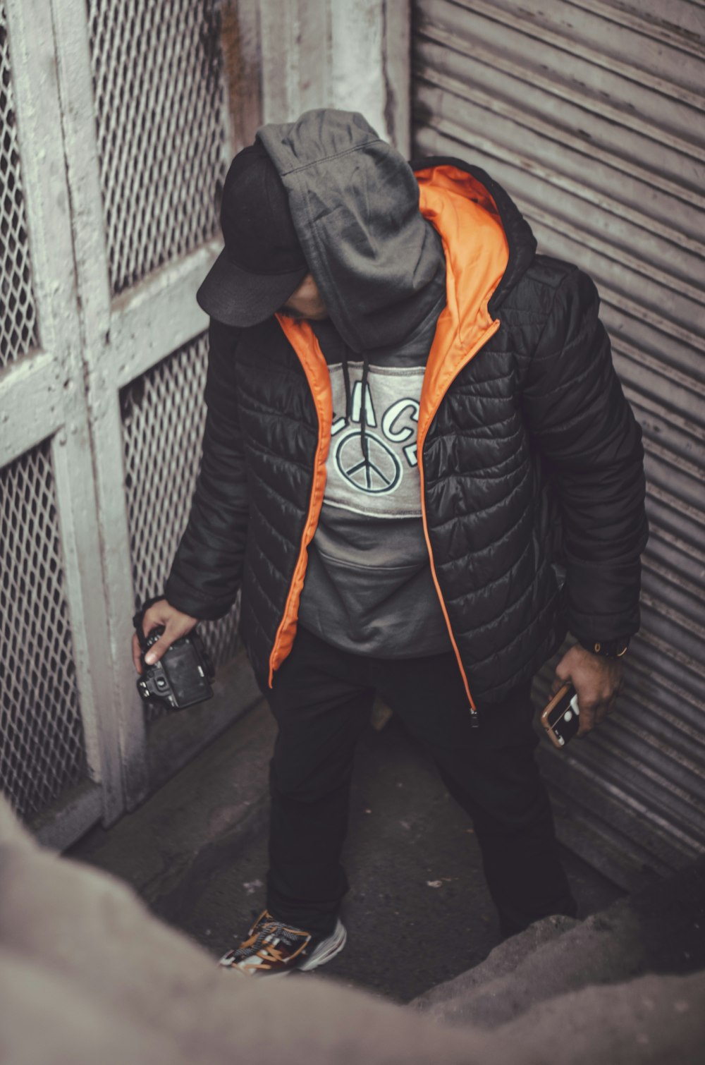 a man in a black jacket and orange hoodie