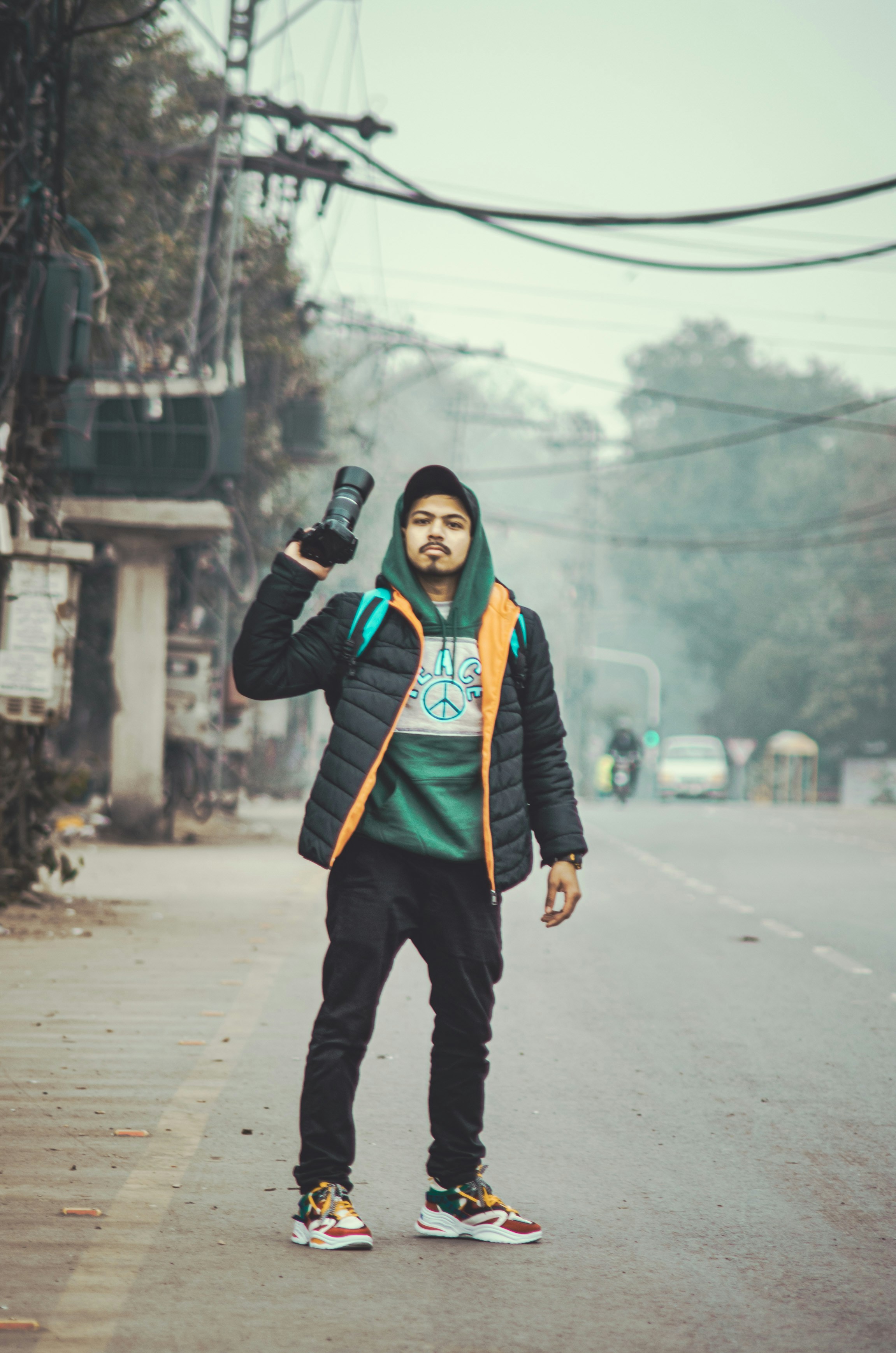 Seorang pria berdiri di pinggir jalan sambil memegang ponsel