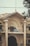 A historic building with decorative columns and ornate architectural details. The structure is marked with the year 1930 at the top. There is a signboard on the balcony, which reads 'Tariq Javaid, Barrister-at-Law, Advocate Supreme Court.' The facade features intricate designs and large archways, with some power lines visible in front. A tree partially obscures the view on the right side.