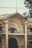 A historic building with decorative columns and ornate architectural details. The structure is marked with the year 1930 at the top. There is a signboard on the balcony, which reads 'Tariq Javaid, Barrister-at-Law, Advocate Supreme Court.' The facade features intricate designs and large archways, with some power lines visible in front. A tree partially obscures the view on the right side.