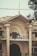 A historic building with decorative columns and ornate architectural details. The structure is marked with the year 1930 at the top. There is a signboard on the balcony, which reads 'Tariq Javaid, Barrister-at-Law, Advocate Supreme Court.' The facade features intricate designs and large archways, with some power lines visible in front. A tree partially obscures the view on the right side.
