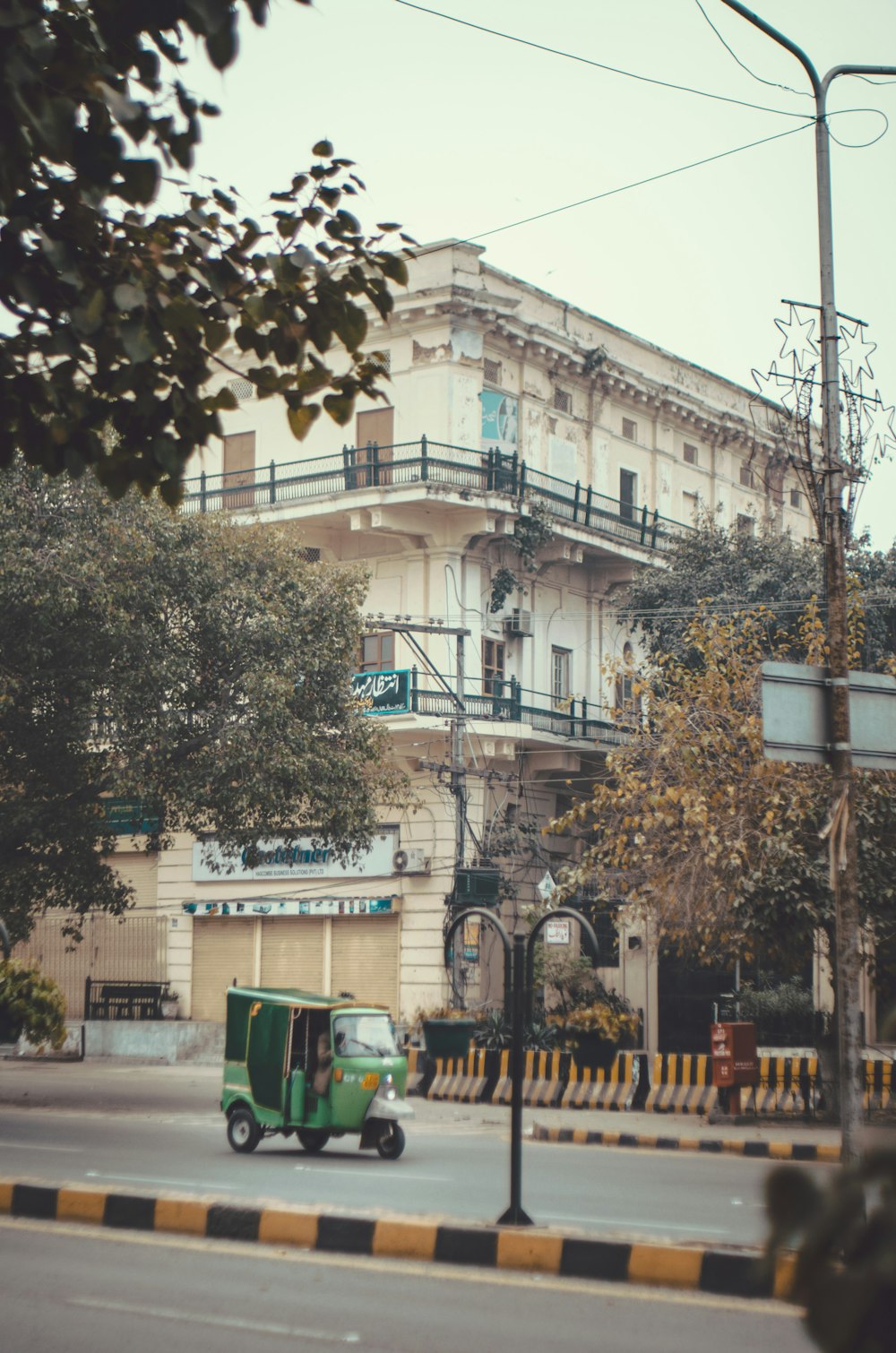 a green truck driving down a street next to a tall building