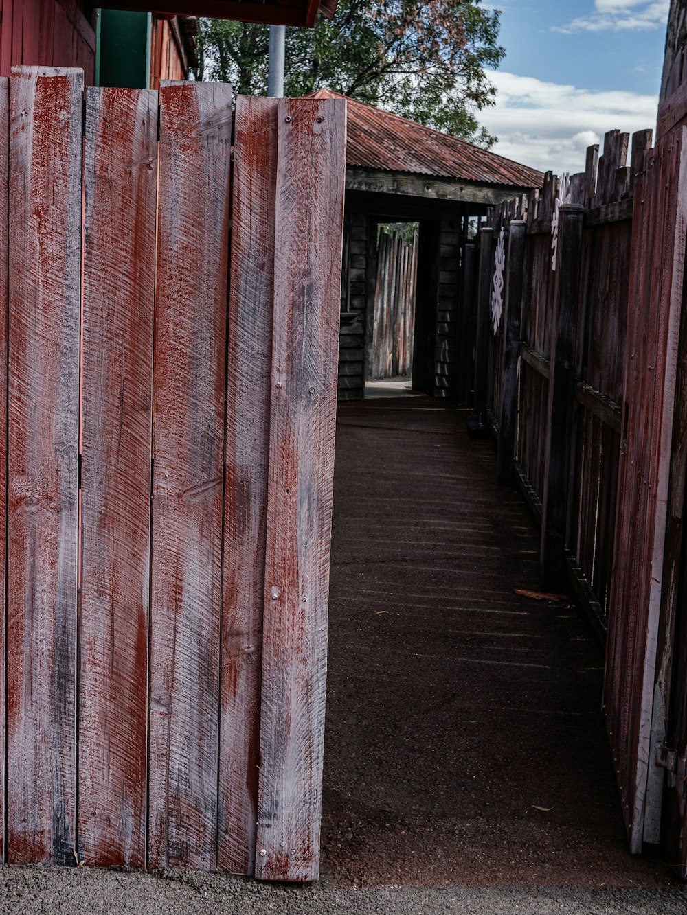 a wooden fence with a red building in the background
