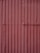 Corrugated metal sheets painted in a faded reddish-brown color with visible seams and texture. Each sheet is vertically aligned with visible rust spots and dents, giving a rugged, industrial appearance.