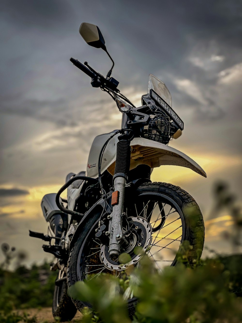 a motorcycle parked on a dirt road under a cloudy sky
