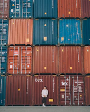 A logistics professional handling customs paperwork with a backdrop of shipping containers.