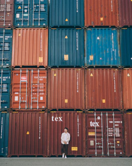 A logistics professional examining shipping documents beside a stack of cargo pallets.