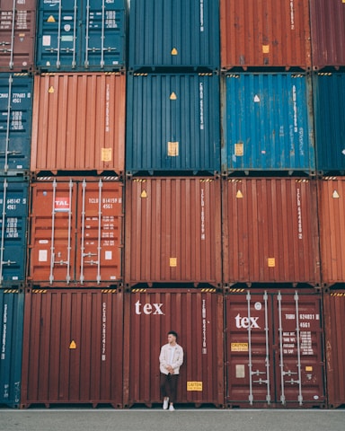 A friendly Debash Logistics team member assisting a customer with shipping documents against a backdrop of cargo containers and a plane.