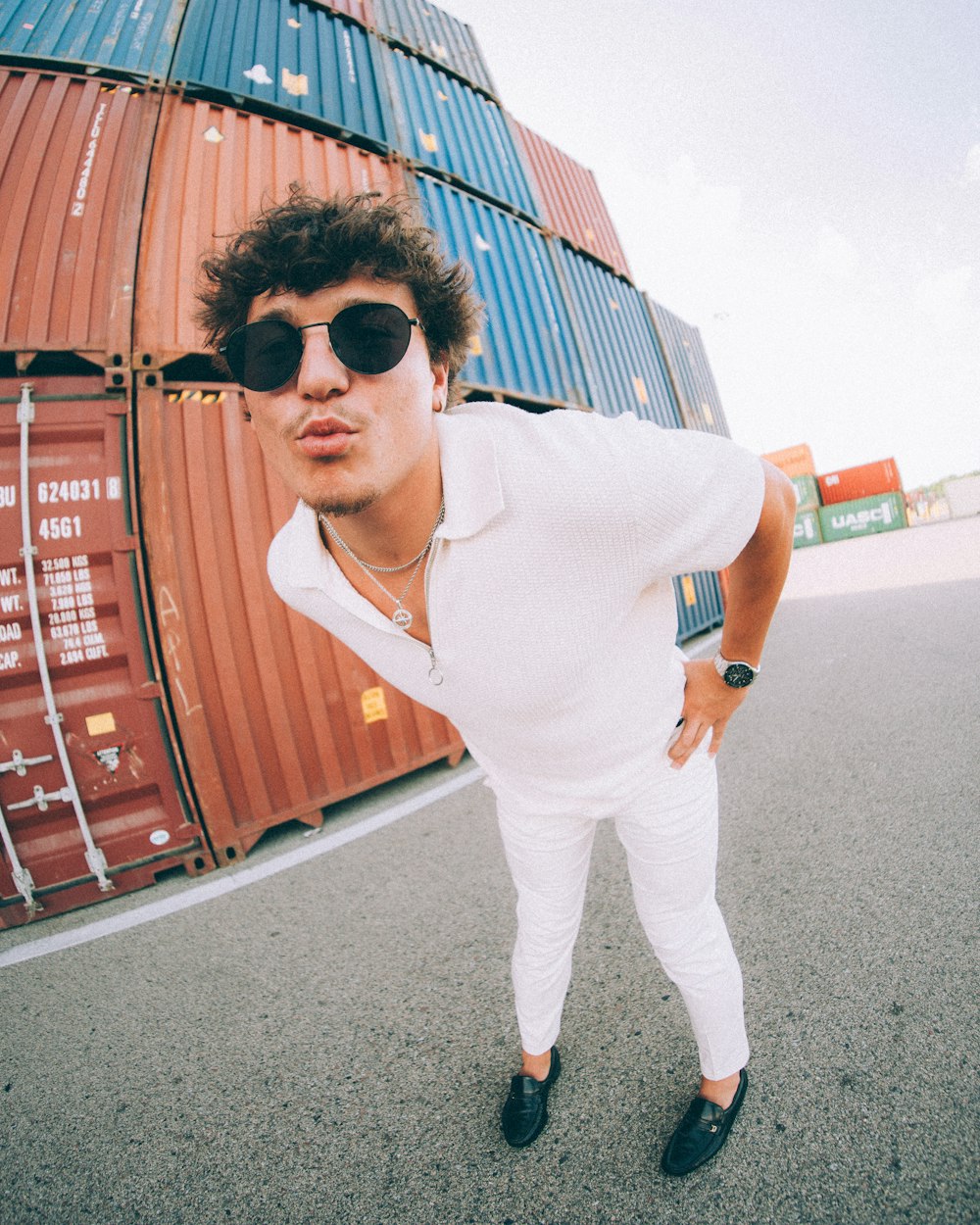 a man wearing sunglasses standing in front of a large container