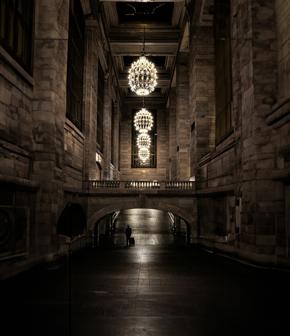 a dark hallway with a chandelier hanging from the ceiling