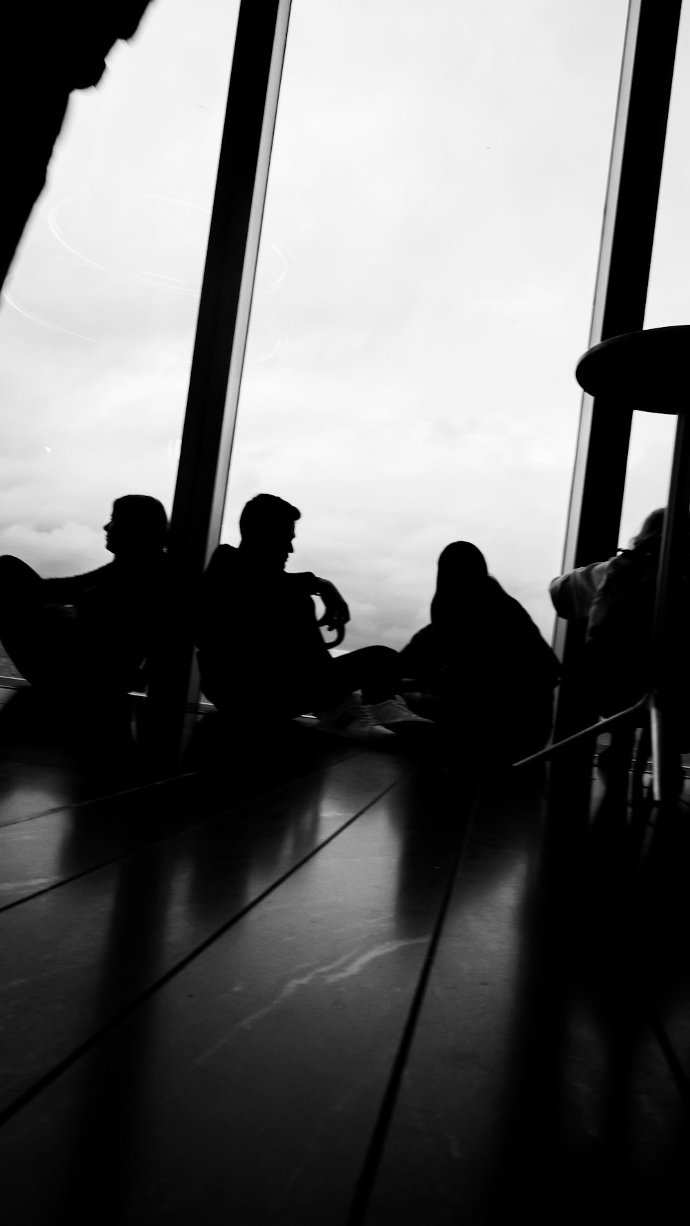 a black and white photo of people sitting in front of a window