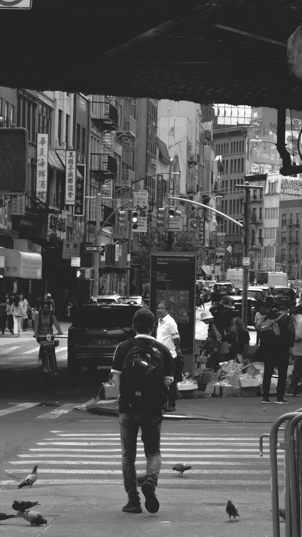 a black and white photo of a man walking across a street