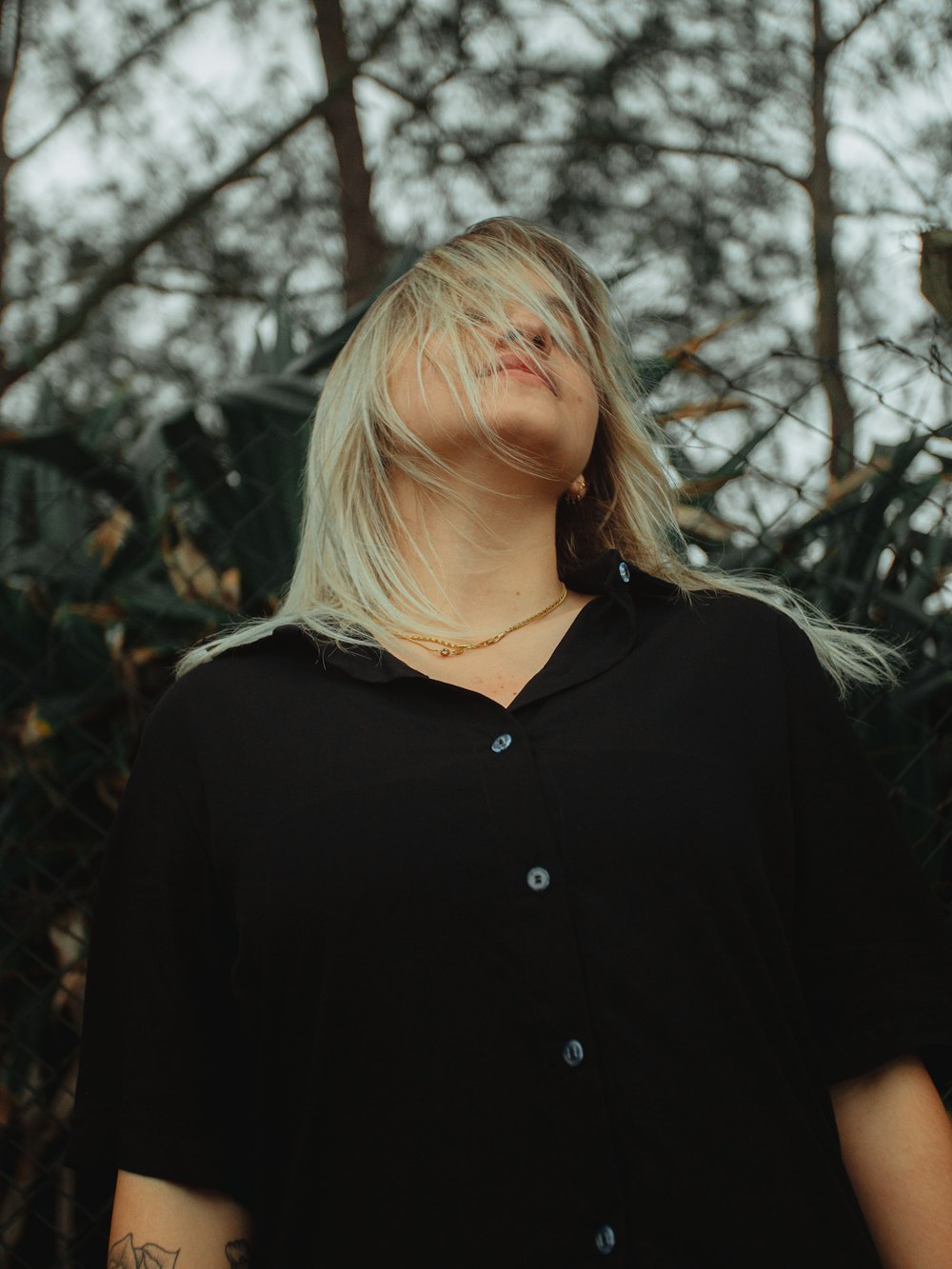 a woman with blonde hair standing in front of trees