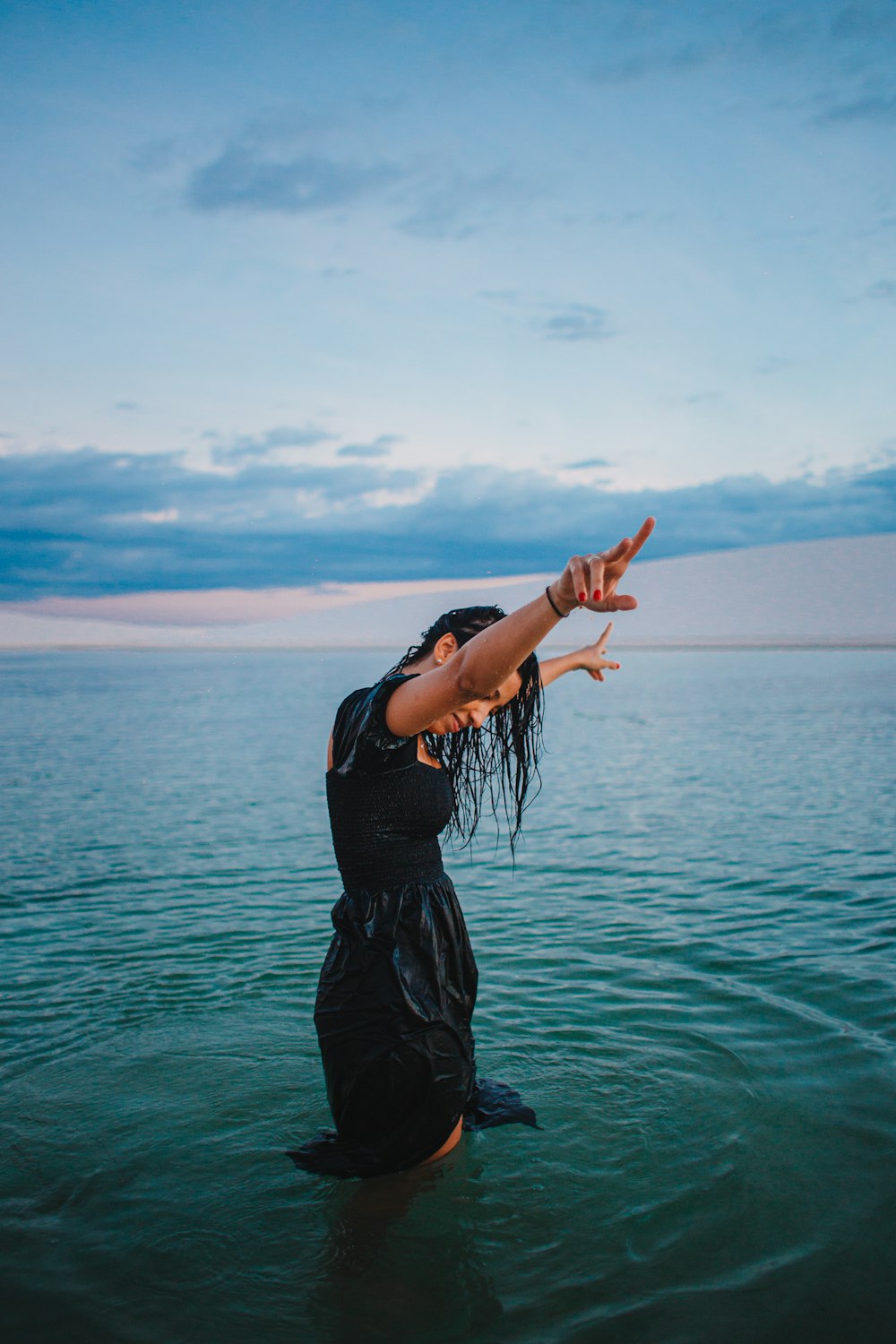 a woman standing in the water with her arms outstretched