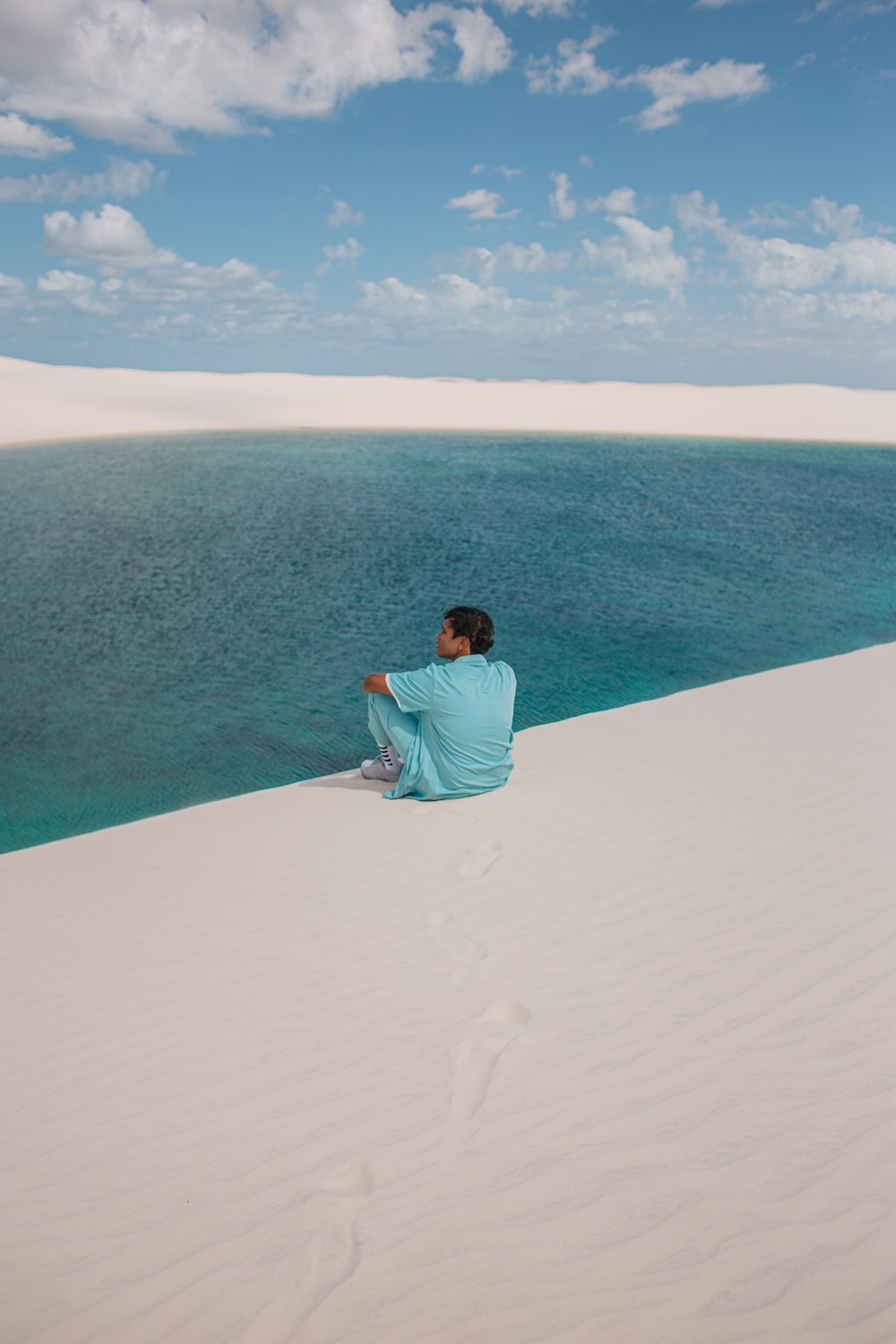 a man sitting on top of a white sand dune