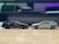 Two scale model cars are positioned facing each other on a smooth wooden surface. The car on the left is black, while the one on the right is silver. The background is blurred, highlighting the models.
