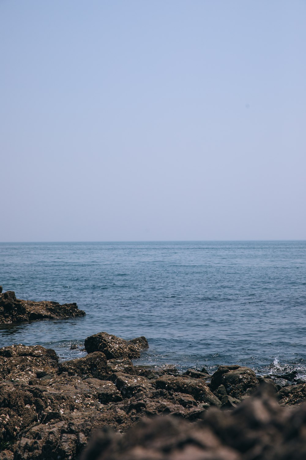 a person standing on a rocky beach next to the ocean