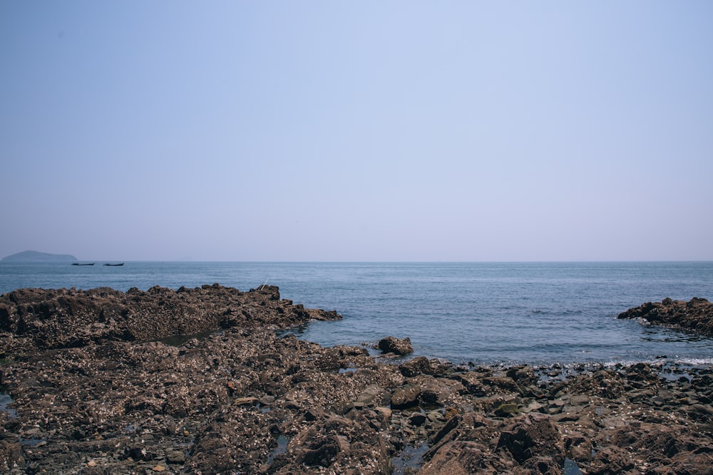 a body of water sitting next to a rocky shore