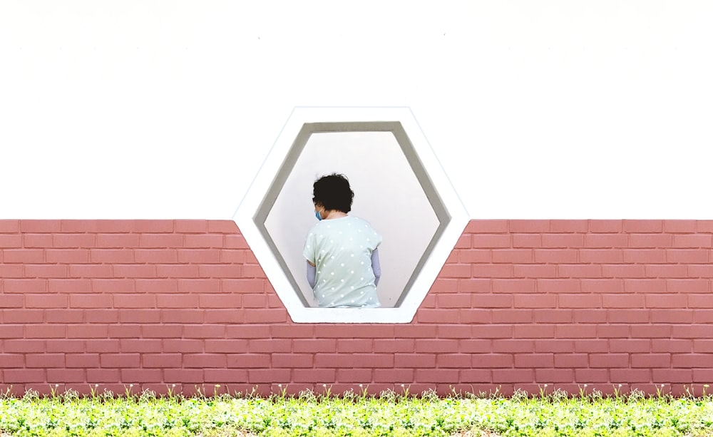 a man looking out of a window in a brick wall