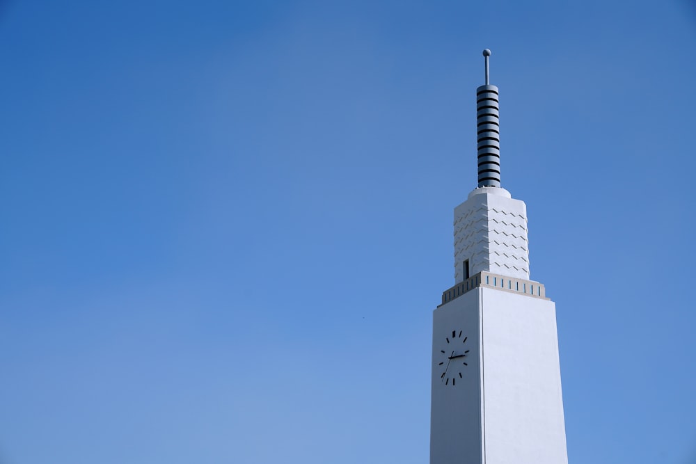 a tall white clock tower with a sky background