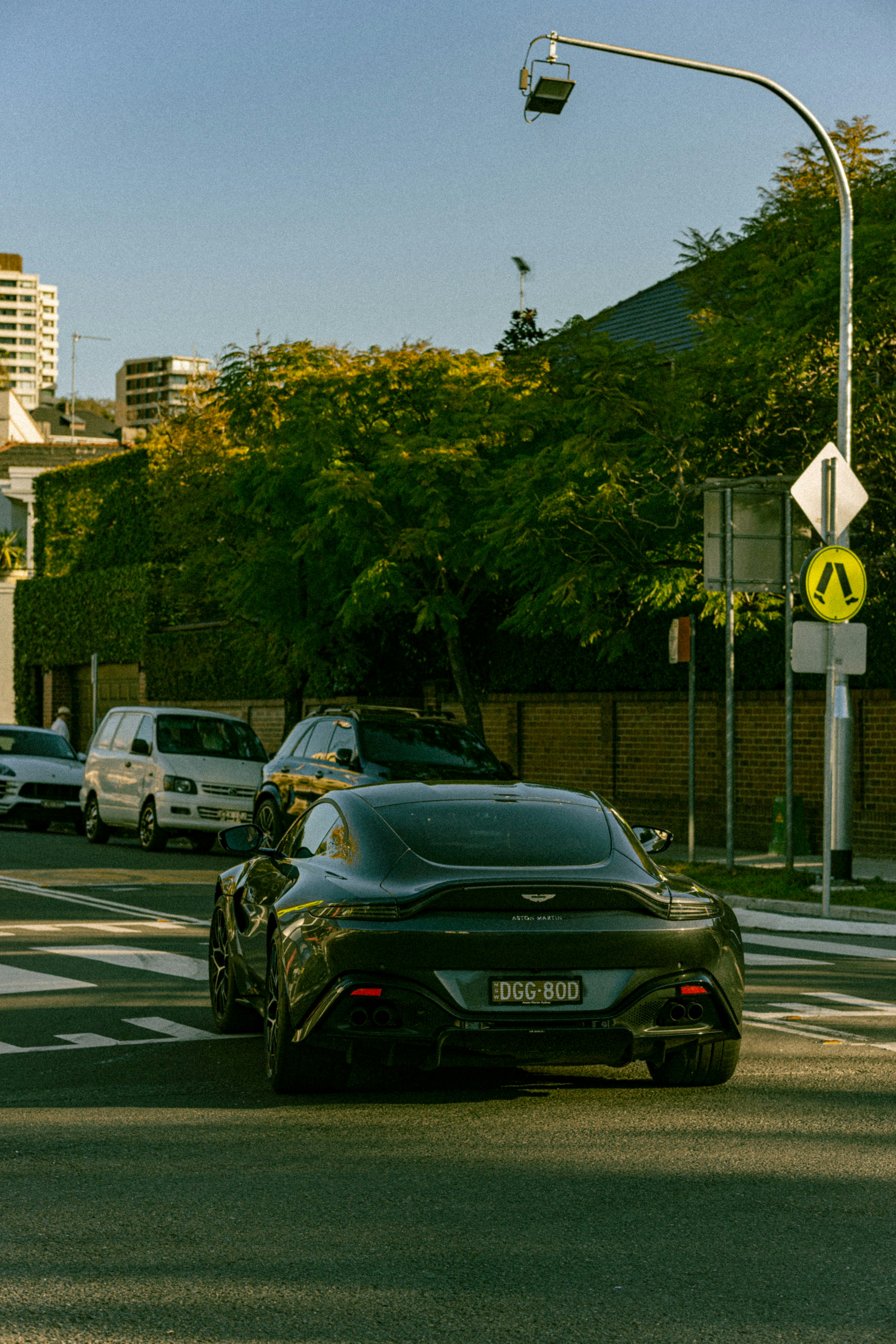 Dark Aston Martin on empty road at night, dramatic rim lighting, deep shadows, moody British GT
