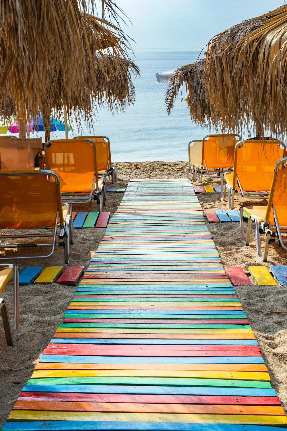 a colorful carpet on the beach with chairs and umbrellas