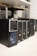 Several desktop computer towers are lined up on the floor next to each other. The computers are placed under a table in an indoor setting. The visible brands include Acer and other unspecified brands. The towers have multiple drive slots and ports visible on the front panels.