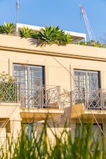 a building with a balcony with plants growing on the balconies