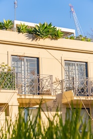 a building with a balcony with plants growing on the balconies