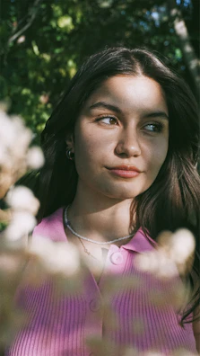 Side view of a young woman in a pastel pink co-ord set smiling softly in natural light