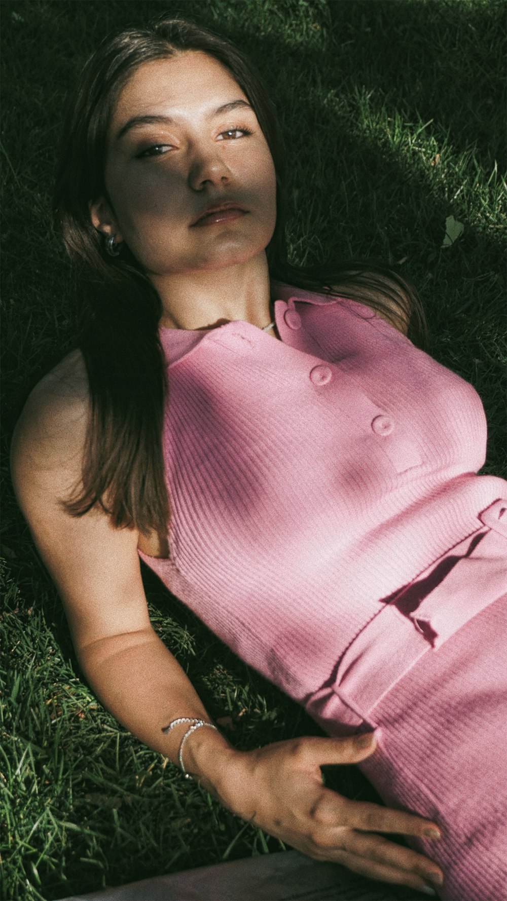 a woman in a pink dress laying in the grass