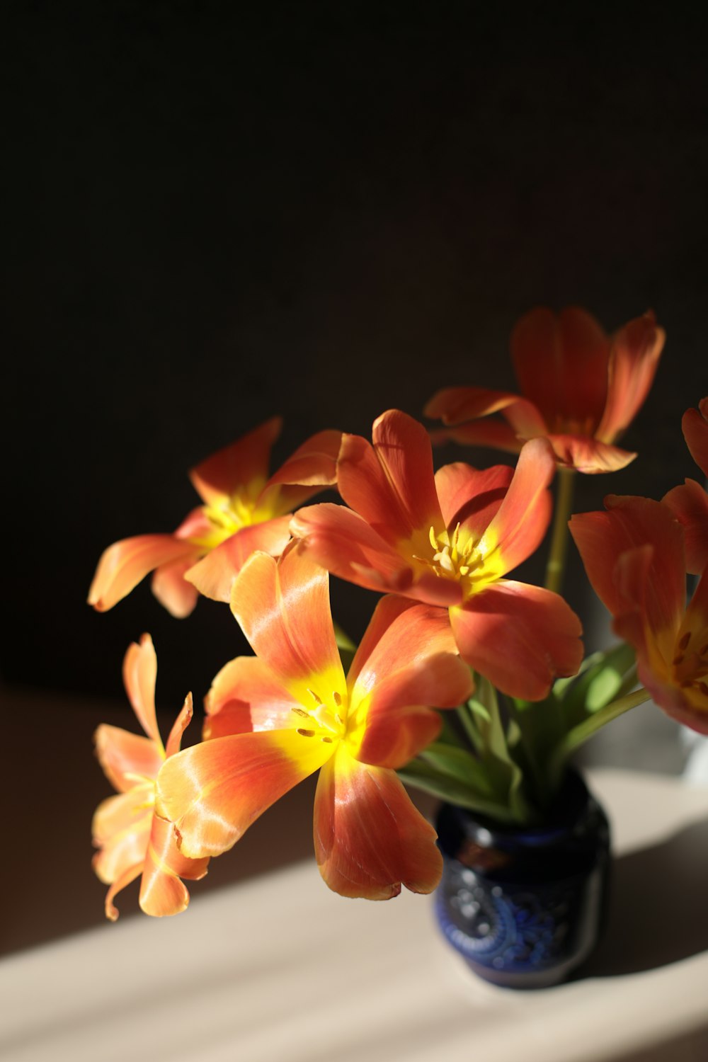 um vaso cheio de flores alaranjadas em cima de uma mesa