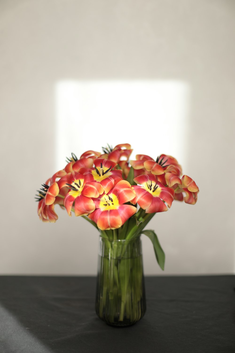 a vase filled with red flowers on top of a table