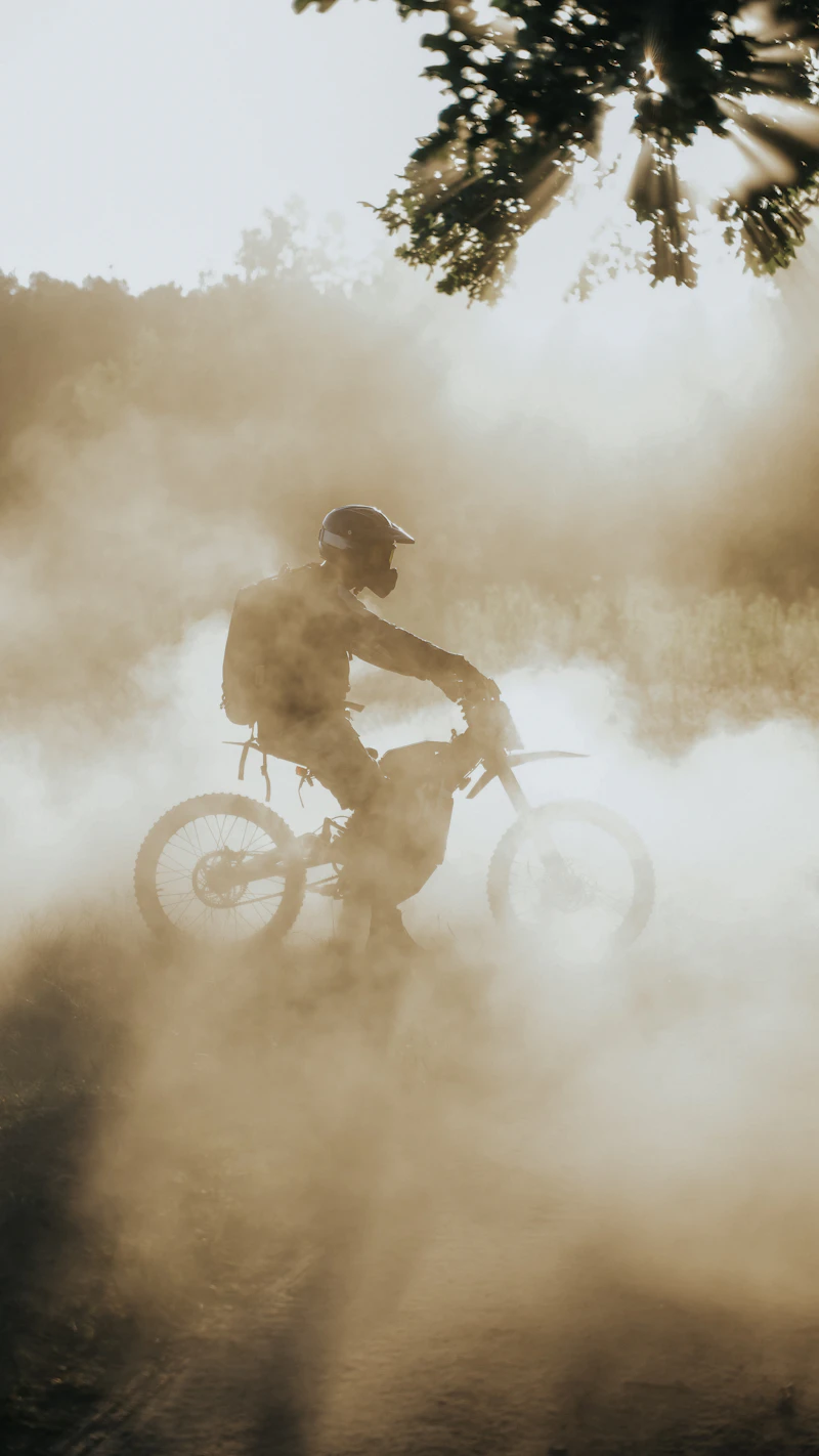 Finished custom electric dirt bike emerging through dust