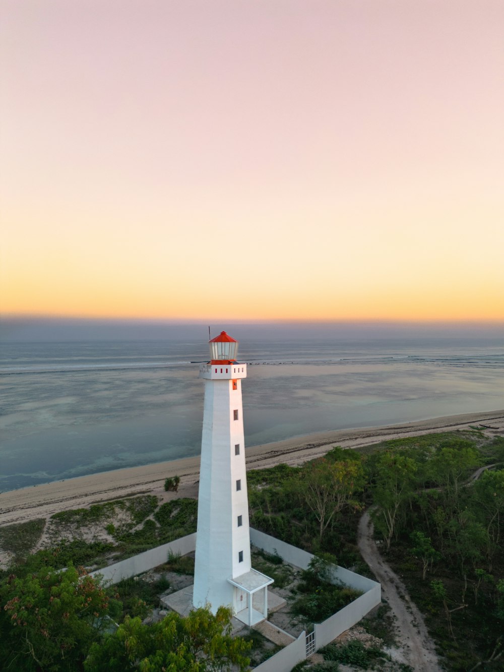 a white light house sitting on top of a lush green field