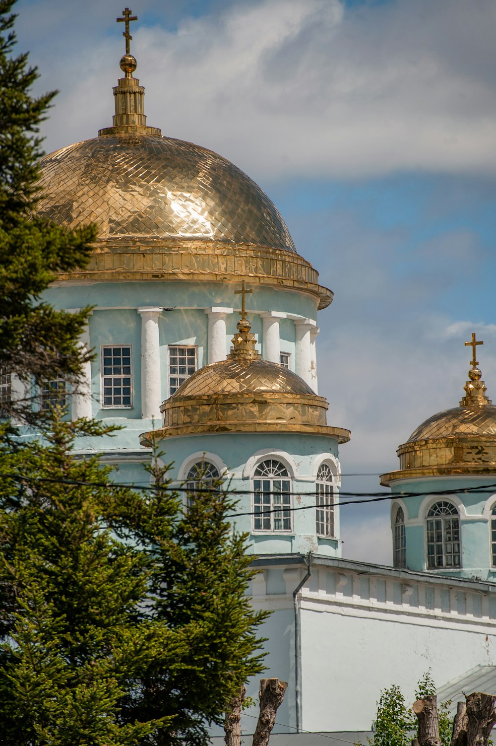a white and gold domed building with trees in front of it