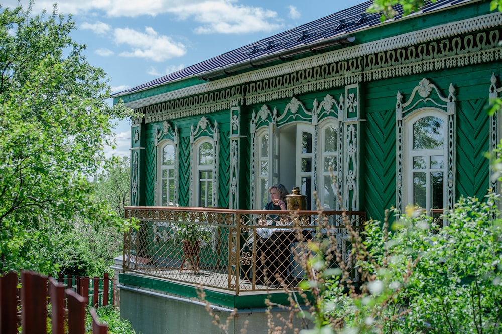 two people sitting on a balcony of a green house