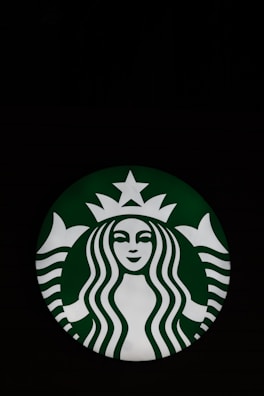 A circular logo featuring a stylized illustration of a mermaid with flowing hair, a crown, and a star above her head. The mermaid is depicted in white on a green background.