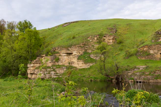 A peaceful riverside beach surrounded by lush green hills in Góis.