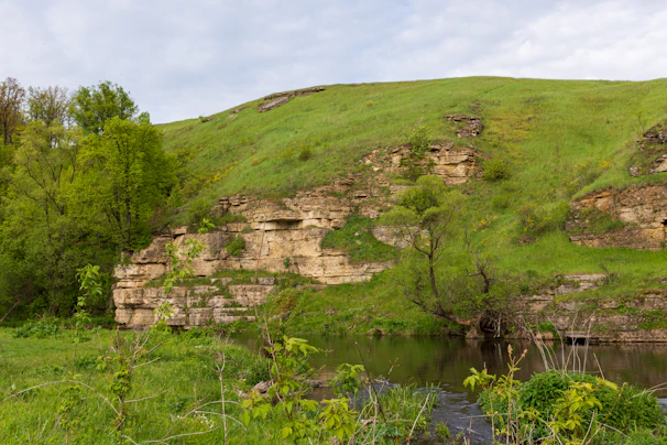 A peaceful riverside beach surrounded by lush green hills in Góis.