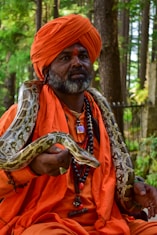 a man in an orange turban holding a snake
