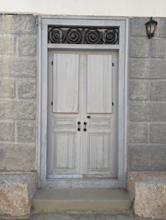 Rustic door set in a brick wall, featuring wrought iron accents and a vintage lantern overhead