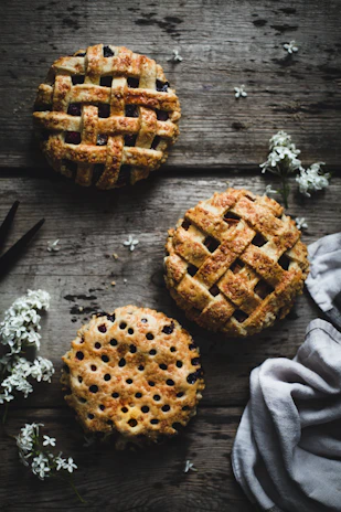 A rustic wooden table displaying an assortment of freshly baked pies and bread from Hodges Homestead.