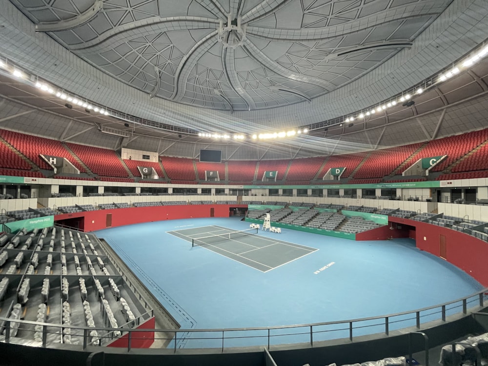 a tennis court with a blue floor and red seats