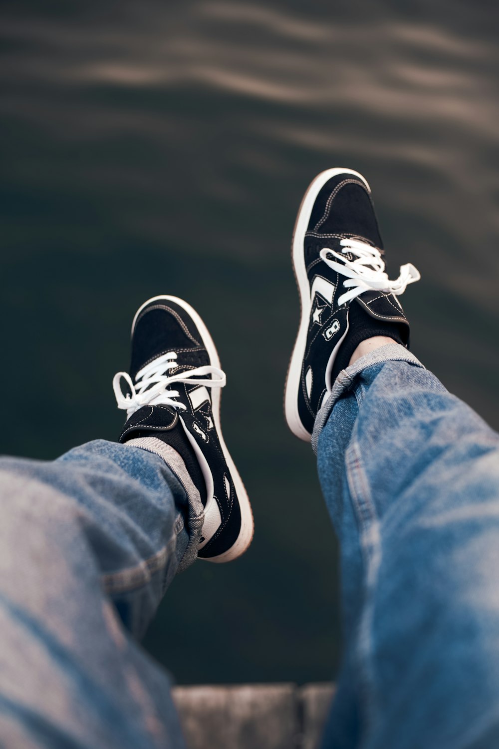 a person with black and white shoes standing on a dock