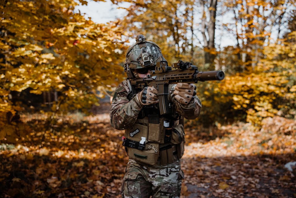 Un hombre camuflado sosteniendo un rifle en una zona boscosa