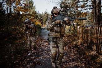 A group of hunters in camouflage gear walking through a dense forest at dawn.