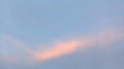 Soft pastel clouds appear against a light blue sky, creating a serene and calming scene. The gentle hues of pink and blue blend harmoniously.