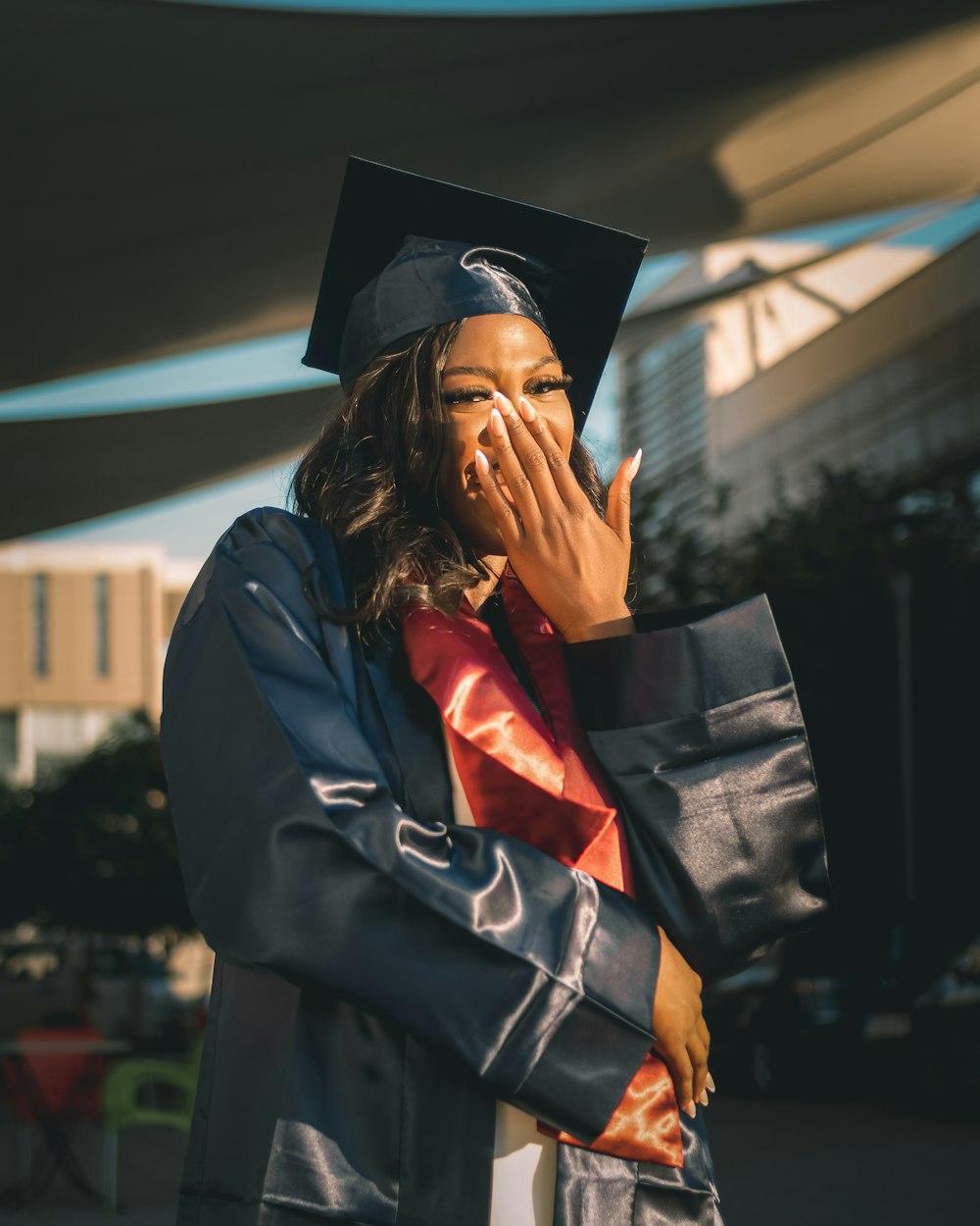 Une femme en robe de graduation se couvre la bouche
